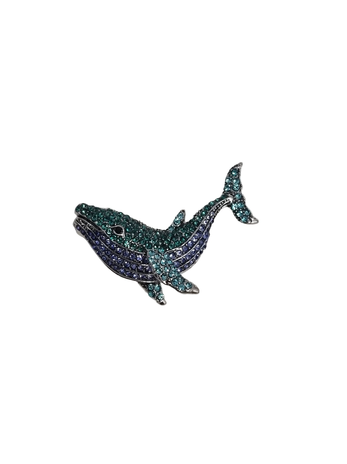Decorative whale-shaped object with gemstones on a textured white surface