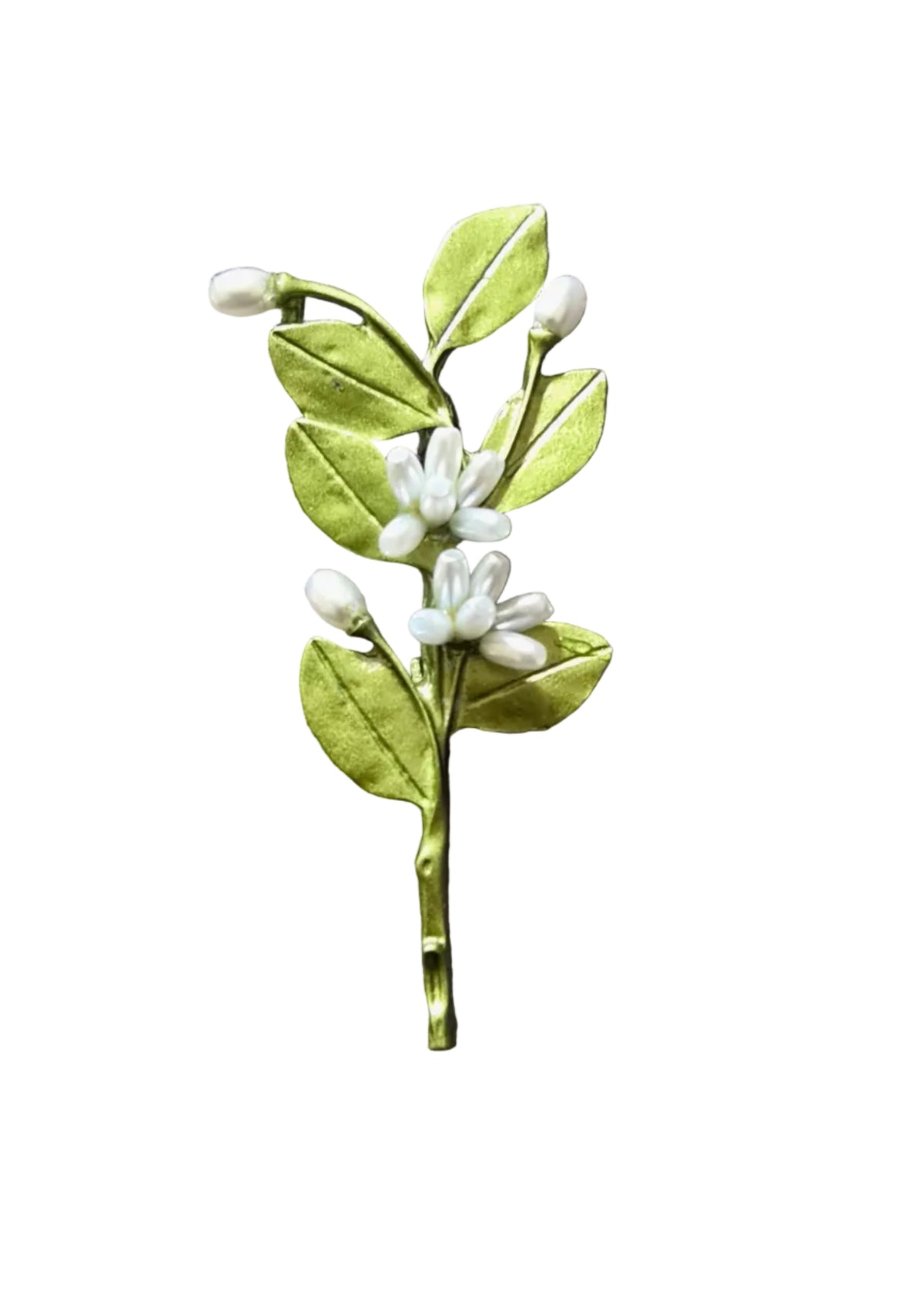 A handmade paper flower hair clip featuring green leaves and white blossoms, placed on a textured gray fabric background.