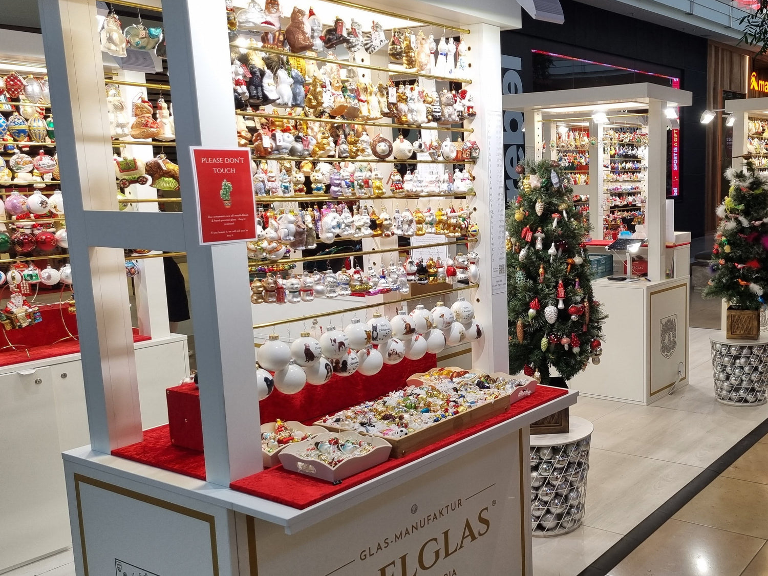 Display of Christmas ornaments in a store with 'EDELGLAS' branding.