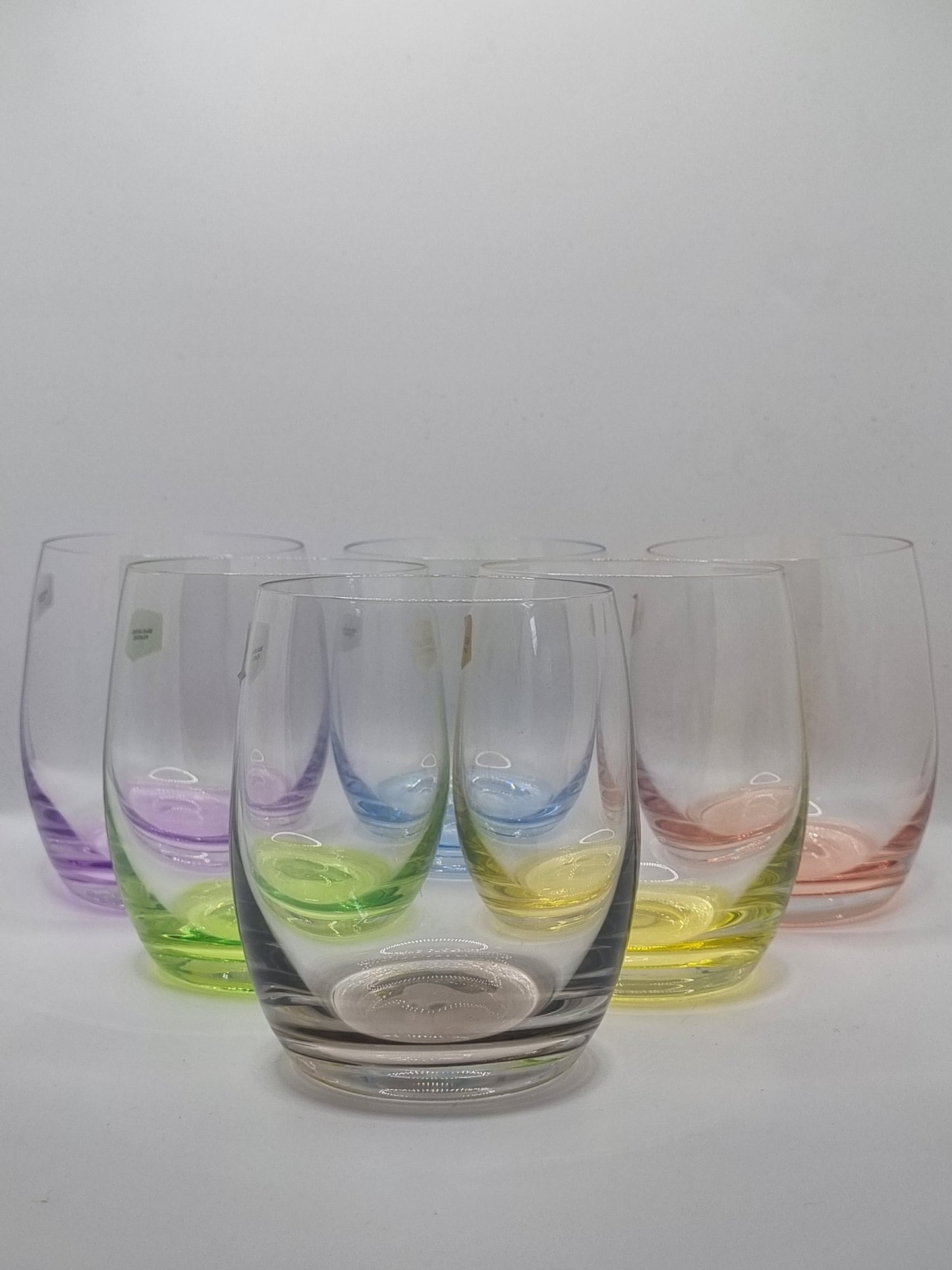 Set of colourful glass whiskey tumblers on a white background