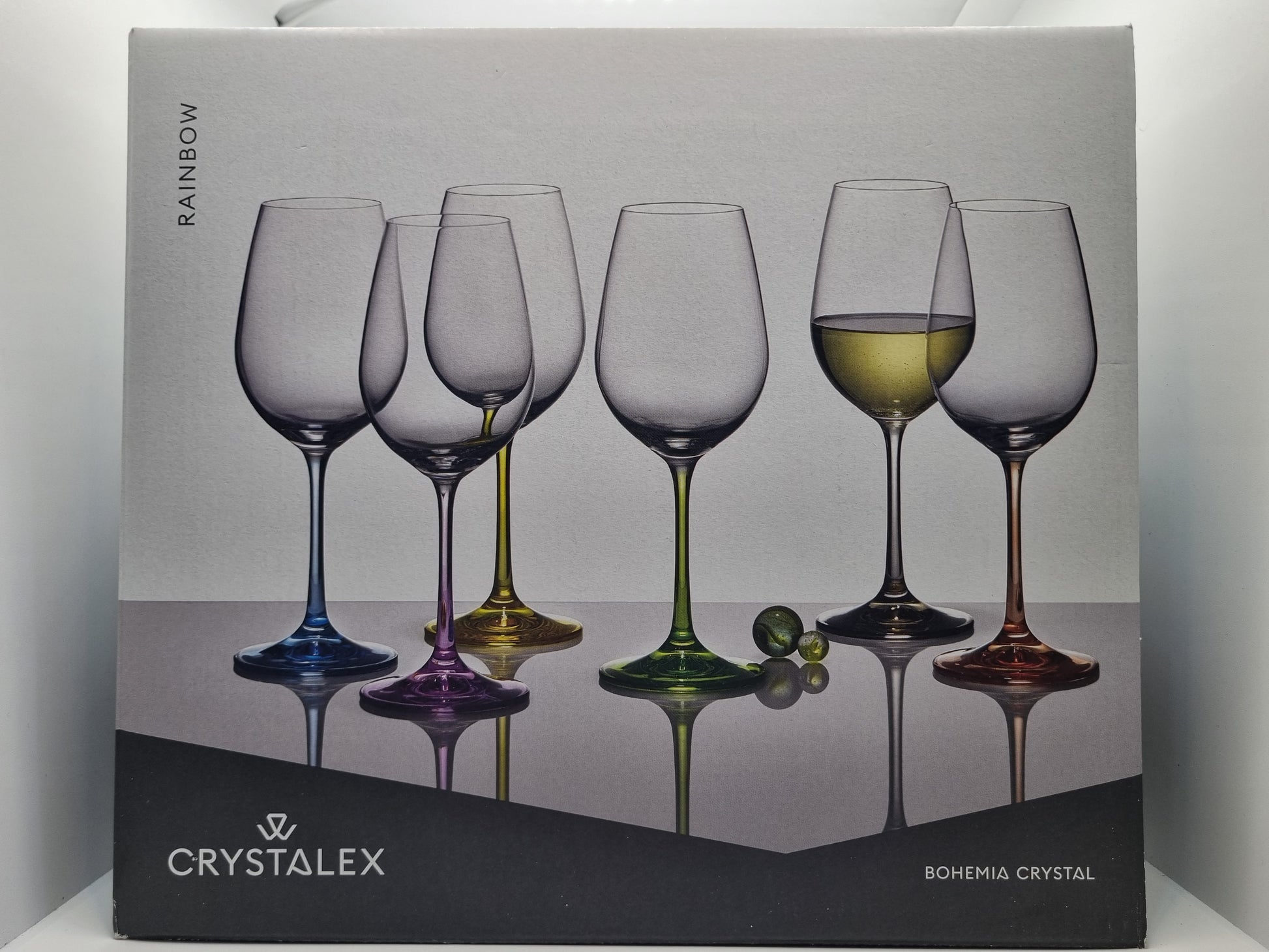 Box of Crystalex wine glasses with a colorful design on a gray background