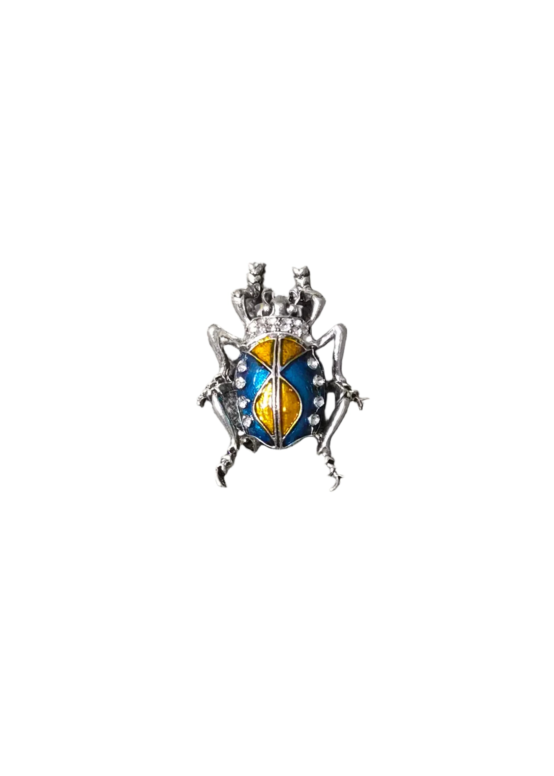 A small beetle-shaped brooch with a silver-toned body and blue, yellow, and white enamel details