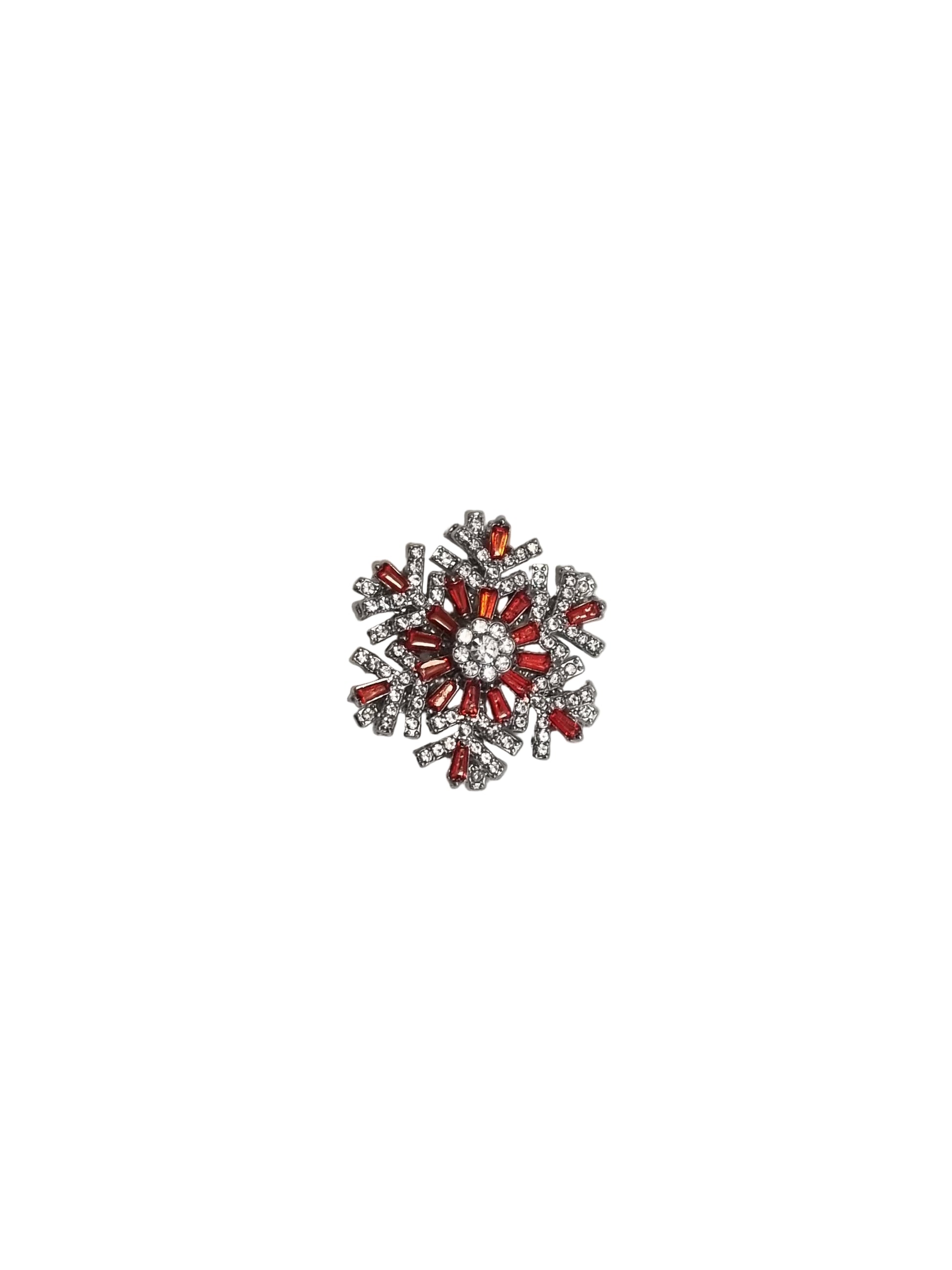 Decorative brooch with red and silver design on a white fabric background