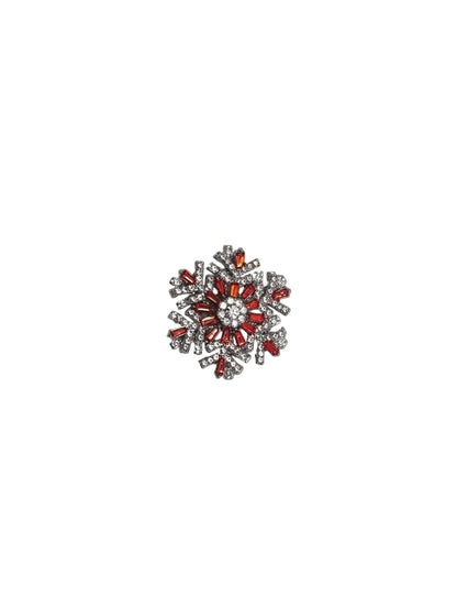 Decorative brooch with red and silver design on a white fabric background