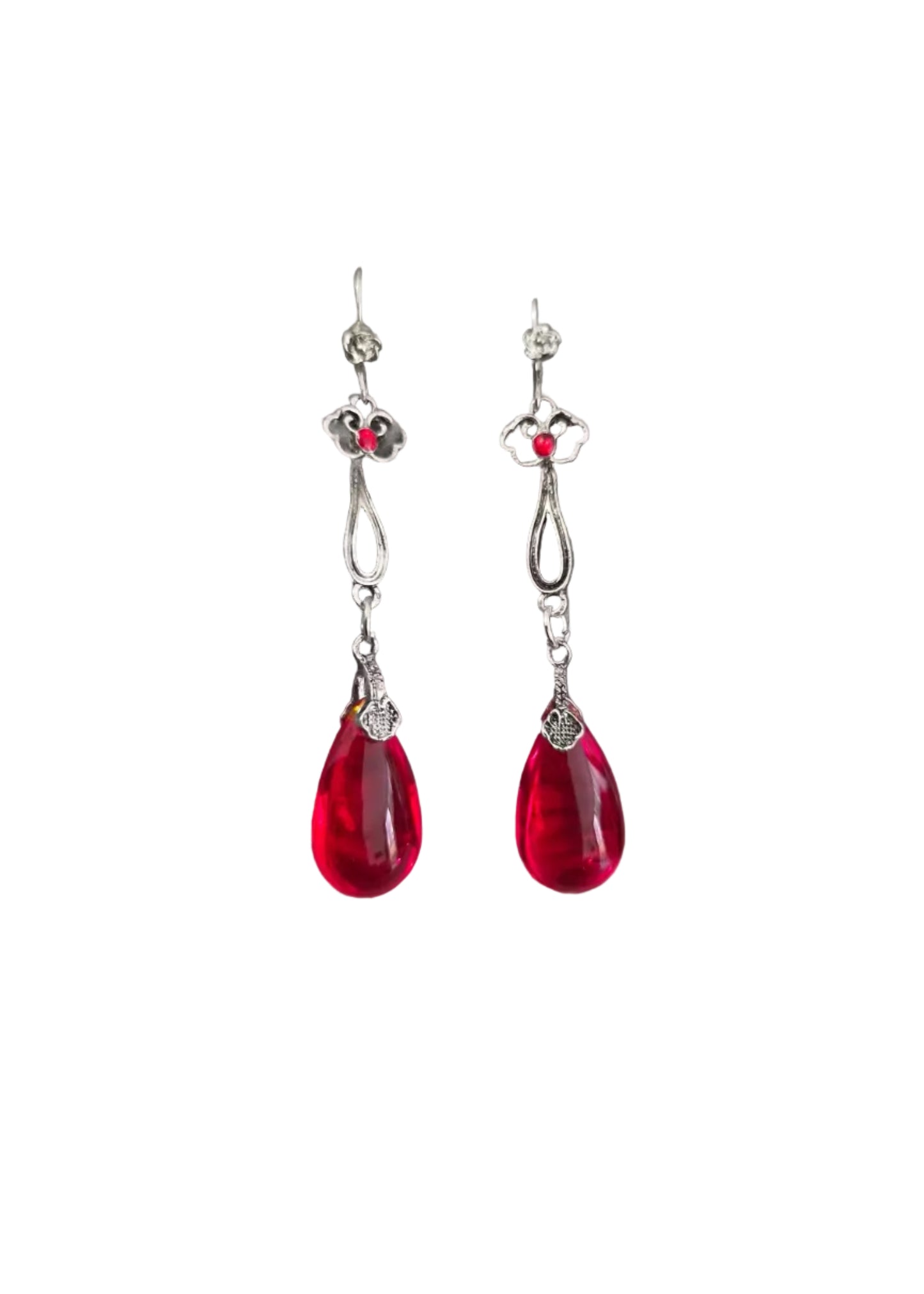 A pair of silver drop earrings with small red gemstone accents and teardrop-shaped red crystal pendants.