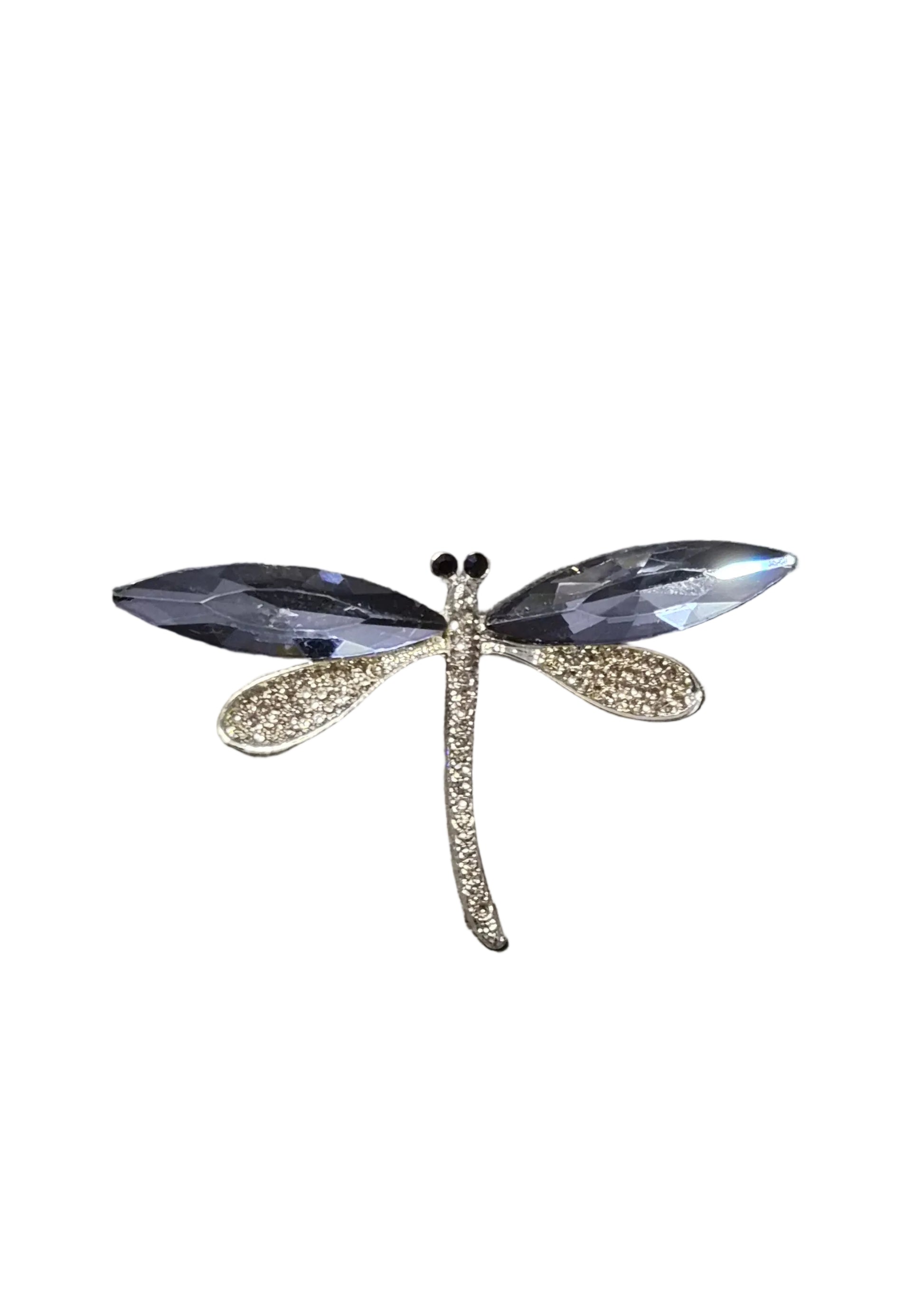 A dragonfly-shaped brooch with clear faceted wings and a textured gold body